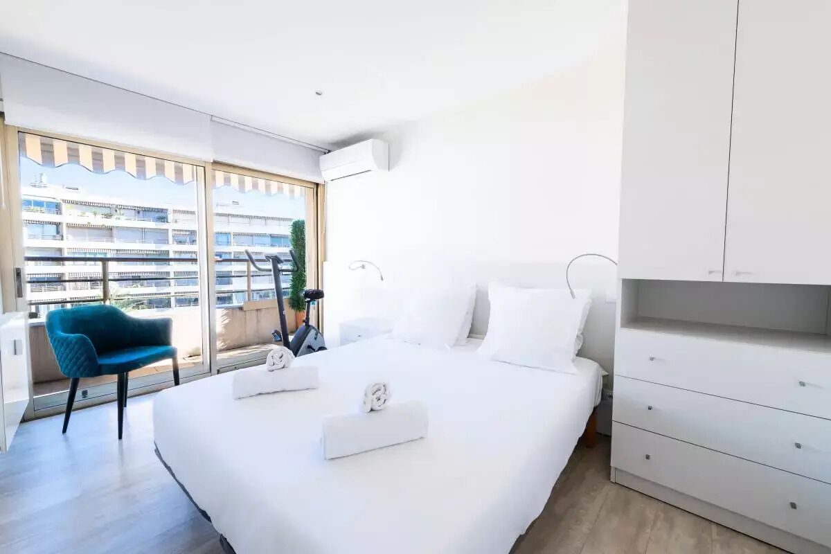 Ein modernes Hotelzimmer mit einem großen Bett, einem Schreibtisch und Blick auf ein Gebäude durch große Fenster.