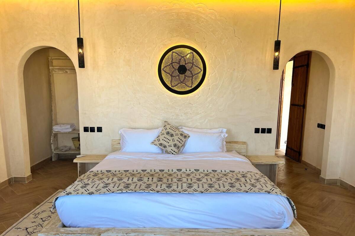 Une chambre à coucher avec un grand lit, une tête de lit à motifs et une décoration murale.