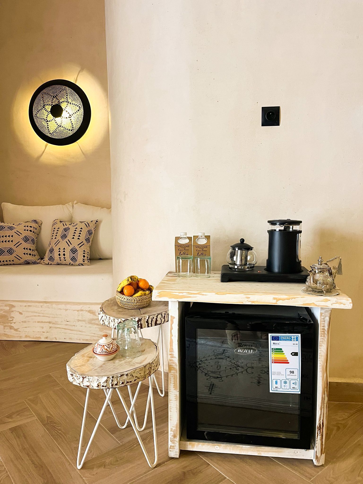 A compact kitchen with a built-in refrigerator, a coffee machine, and a small dining table.