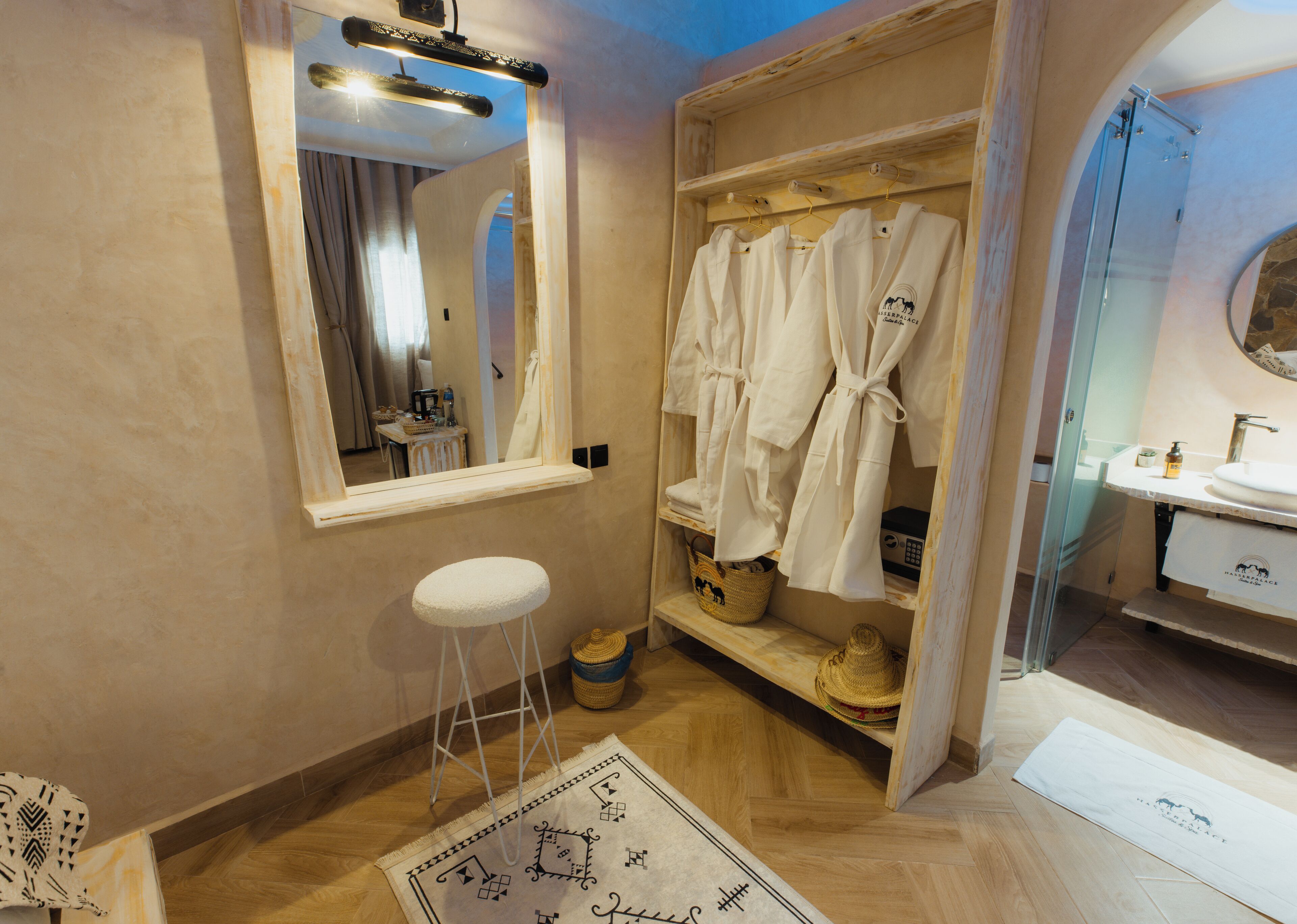 Une salle de bain avec un meuble-lavabo en bois, un miroir, un porte-peignoir et une petite étagère sur laquelle se trouve un panier en osier.