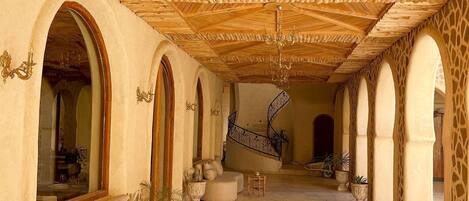 A spacious interior with a high wooden ceiling, a central staircase, and a seating area with a sofa and a small table.