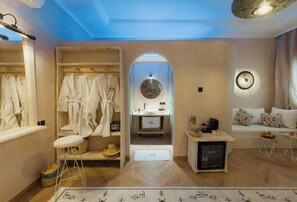 A modern bathroom with a vanity, a mirror, and a seating area with cushions.