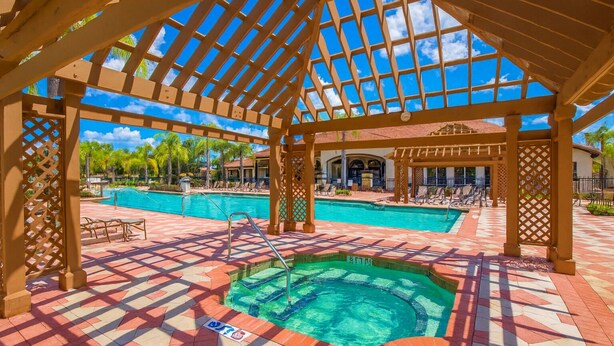 A covered outdoor swimming pool area with a pergola structure, tiled flooring, and lounge chairs. - Family Home 20 min Disney - 4BR - Heated Pool - BBQ (Kissimmee)
