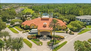 A large building with a red roof, surrounded by well-maintained gardens and a central fountain. - Family Home 20 min Disney - 4BR - Heated Pool - BBQ (Kissimmee)