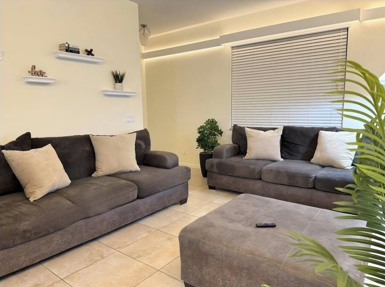 A living room with two grey sofas, a coffee table, and a potted plant.