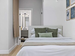 A bedroom with a bed, a nightstand, a mirror, and a door leading to another room. - 5BR3B By Subway Downtown (Boston)