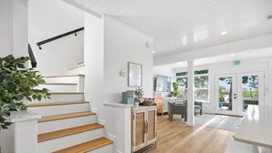 Un interior moderno con una escalera de madera, una zona de cocina y un espacio para comer con vistas.