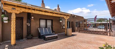 Un área de patio techada con una pérgola de madera, un banco y plantas en macetas.