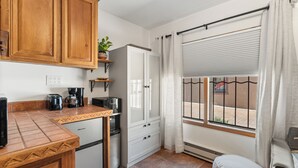 A compact kitchen with wooden cabinets, a coffee maker, and a refrigerator.