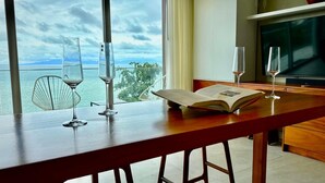 Ein Zimmer mit Holztisch, zwei Weingläsern, einem offenen Buch und einem Fernseher.
