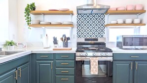 Une cuisine moderne avec des armoires de couleur turquoise, une cuisinière en acier inoxydable et un four à micro-ondes.