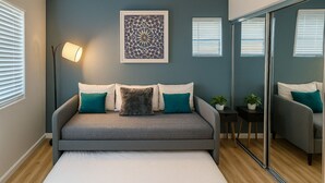 Une chambre à coucher avec un lit, une table de chevet, une lampe et un grand miroir.