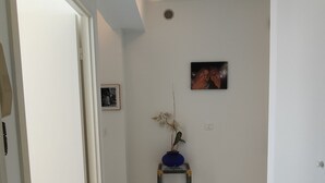 En gang med marmorgulv, et lille bord med en vase og en loftslampe.