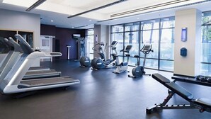Een moderne sportschool met loopbanden, elliptische trainers en een bank.