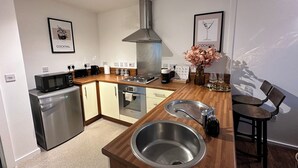 Una cucina compatta con forno a microonde, tostapane, macchina del caffè e lavello.
