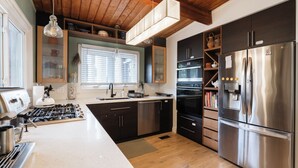 Una cucina moderna con frigorifero in acciaio inossidabile, forno integrato e piano cottura a gas.