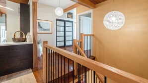 Una scala in legno con ringhiera, un bancone di legno scuro e un lampadario.
