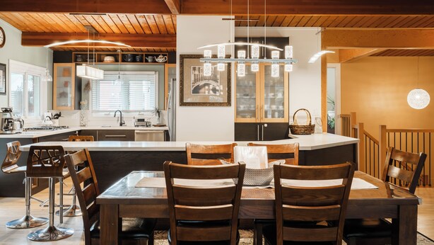 Una cucina moderna con travi in legno, un'isola centrale e luci a sospensione.