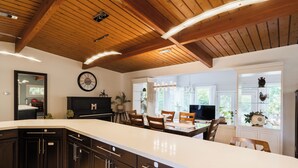 Una cucina con pensili scuri in legno, un'isola grande e un soffitto in legno.
