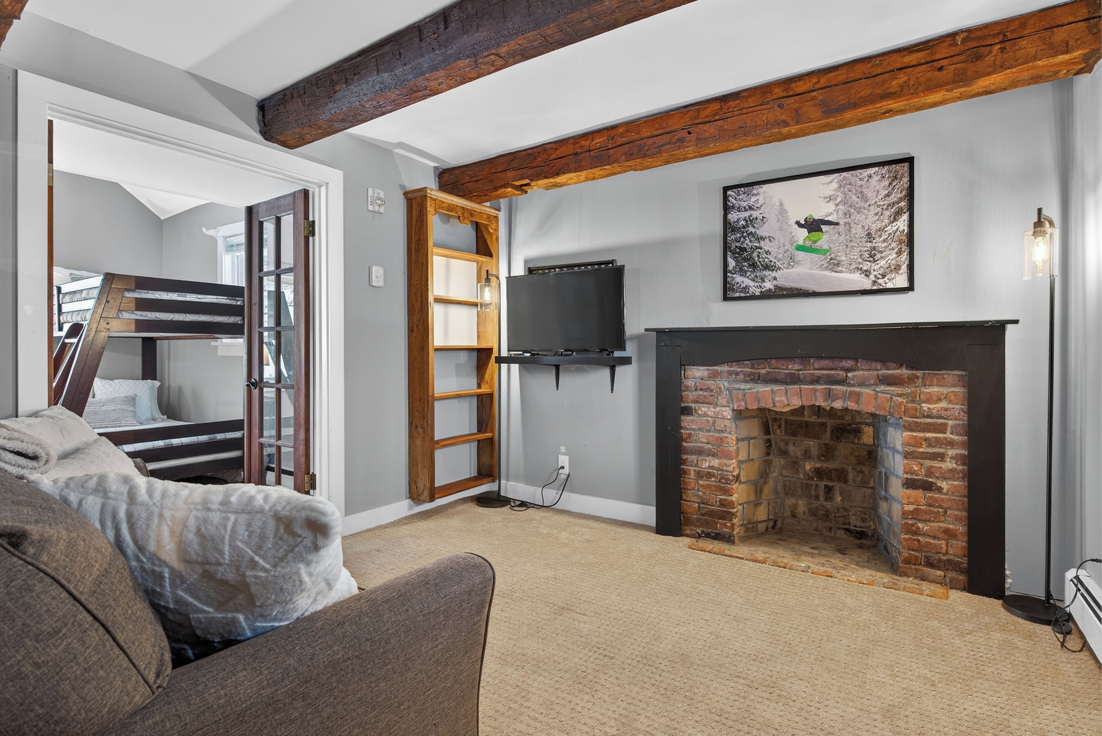 Un salon chaleureux avec une cheminée, un téléviseur et un escalier menant à une chambre à coucher située en mezzanine.