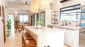A modern kitchen with a marble island, wooden stools, and a large window. - Private Home with Luxury Pool and Outdoor Living (Yalcón)