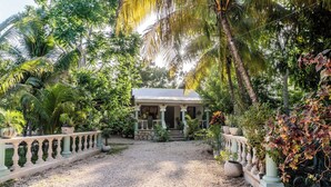 A house with a gravel driveway, surrounded by lush greenery and palm trees. - Private Home with Luxury Pool and Outdoor Living (Yalcón)