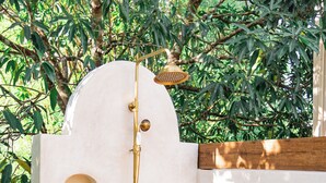 A white outdoor shower with a wooden roof, surrounded by greenery. - Private Home with Luxury Pool and Outdoor Living (Yalcón)