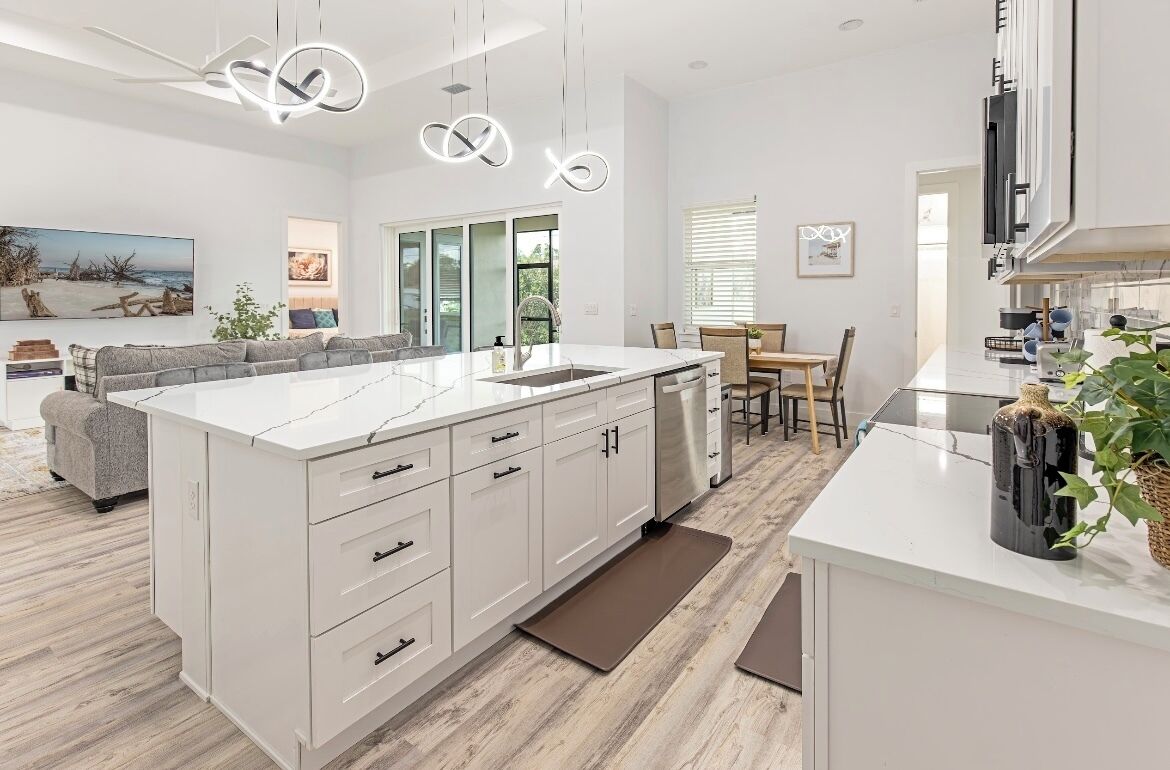 A modern kitchen with white cabinetry, a large island, and pendant lighting.
