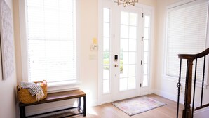 A bright hallway with a bench, a door with a light switch, and a rug on the floor. - Luxury Retreat in Reunion w/Private Pool and Hot Tub - Sleeps 10 (Kissimmee)