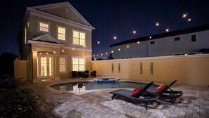 A two-story house with a swimming pool, outdoor seating, and string lights. - Luxury Retreat in Reunion w/Private Pool and Hot Tub - Sleeps 10 (Kissimmee)