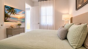 A bedroom with a bed, a nightstand, a lamp, a painting, and a window with curtains. - Private Cozy and relaxing 1-bedroom unit with living room kitchen full bath more (North Port)