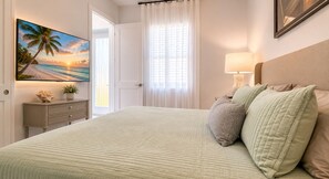 A bedroom with a bed, a nightstand, a lamp, a painting, and a window with curtains. - Private Cozy and relaxing 1-bedroom unit with living room kitchen full bath more (North Port)
