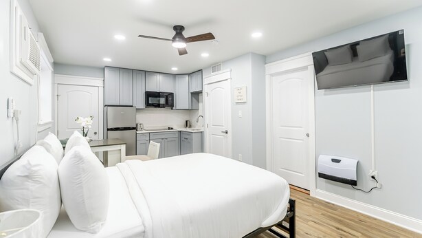 A modern bedroom with a bed, bedside table, and a small desk area. - S. Philly Studio Minutes - Center City Passyunk Sq and More! (Philadelphia)
