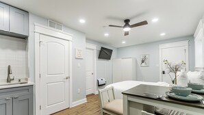 A modern kitchen with grey cabinets, a white countertop, and a dining area with a table and chairs. - S. Philly Studio Minutes - Center City Passyunk Sq and More! (Philadelphia)