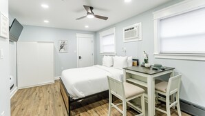 A bedroom with a bed, a desk, two chairs, a ceiling fan, and a window with blinds. - S. Philly Studio Minutes - Center City Passyunk Sq and More! (Philadelphia)