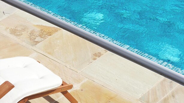 A poolside area with two white lounge chairs and a tiled pool edge.