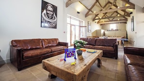 A spacious living room with two brown leather sofas, a wooden coffee table, and a large window.