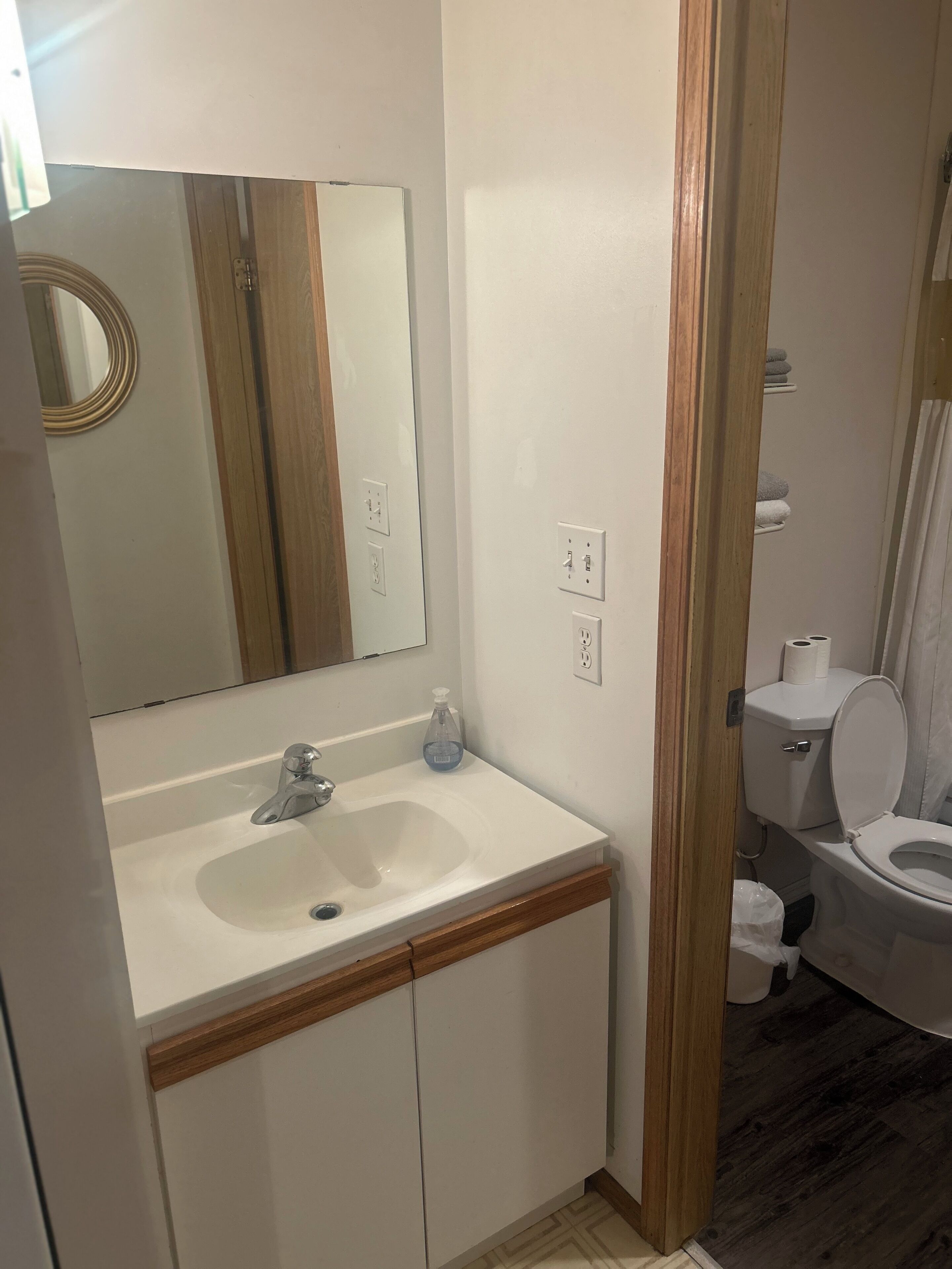 Une salle de bain avec un lavabo blanc, un miroir et des toilettes.