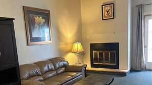 Un salon avec un canapé en cuir, une table basse, une cheminée et une lampe.