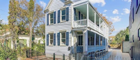 A two-story house with a balcony, a front porch, and a small front yard.