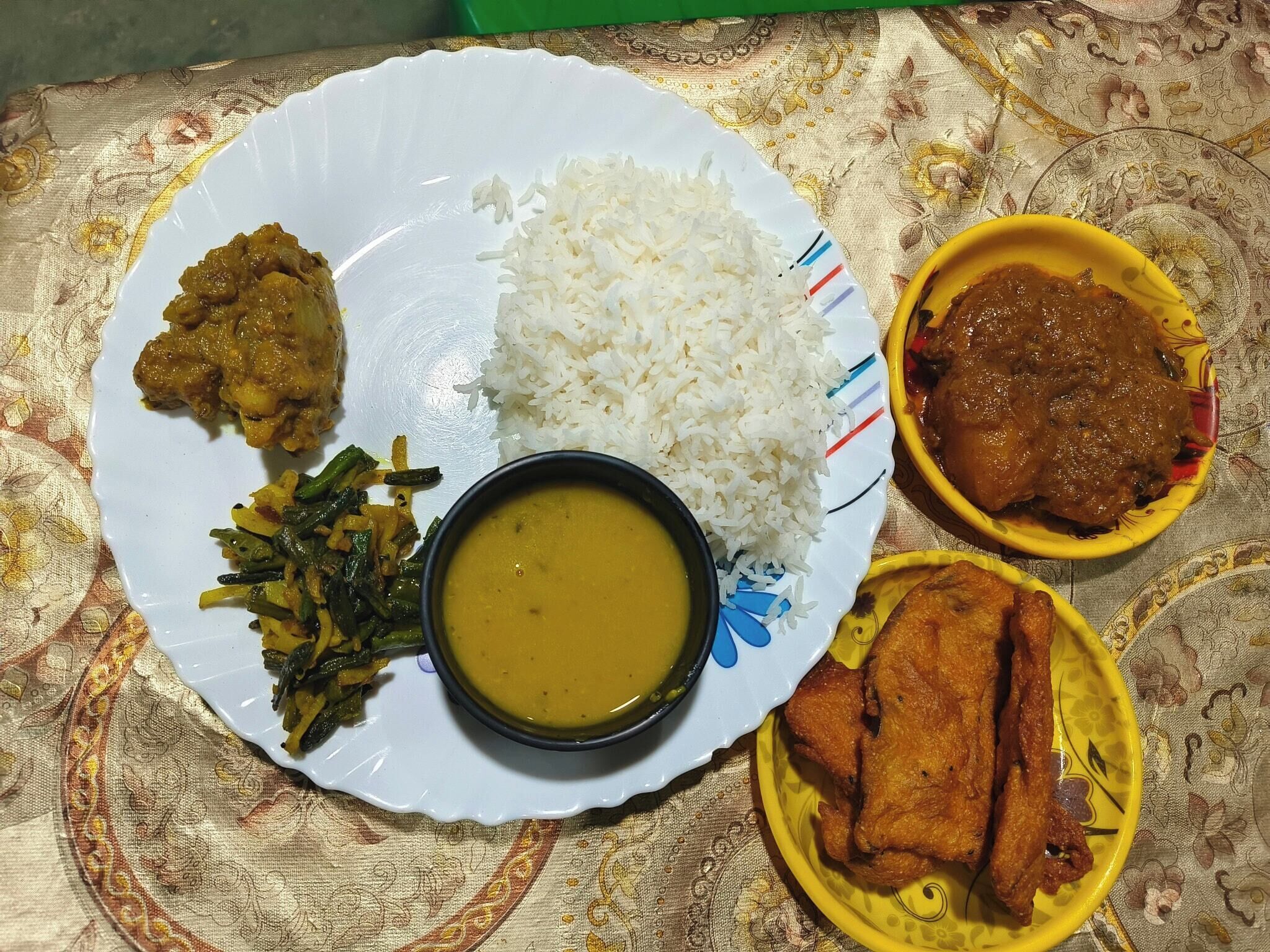 Un plato con arroz blanco, un curry, un tazón de sopa y alimentos fritos.