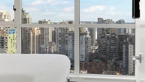 Une pièce dotée d’une grande fenêtre donnant sur un paysage urbain avec de nombreux immeubles de grande hauteur.
