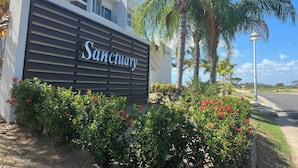 A building with a sign reading "Sanctuary" surrounded by lush greenery and palm trees. - Playa Caracol, a Happy Beach (Punta Chame)