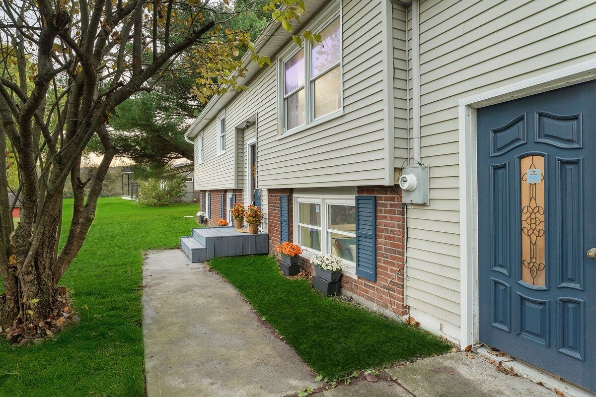 A two-story house with a front porch, a blue door, and a brick section on the lower level.