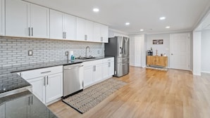 A modern kitchen with white cabinets, a black countertop, and a stainless steel refrigerator. - Near Ithaca! Hot Tub! Karaoke Room! Sleeps 10! Dogs ok! (Newfield)