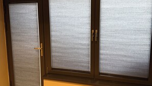 Una habitación con puerta de cristal corredera que tiene paneles de vidrio esmerilado, suelo de madera y pared de color oscuro.