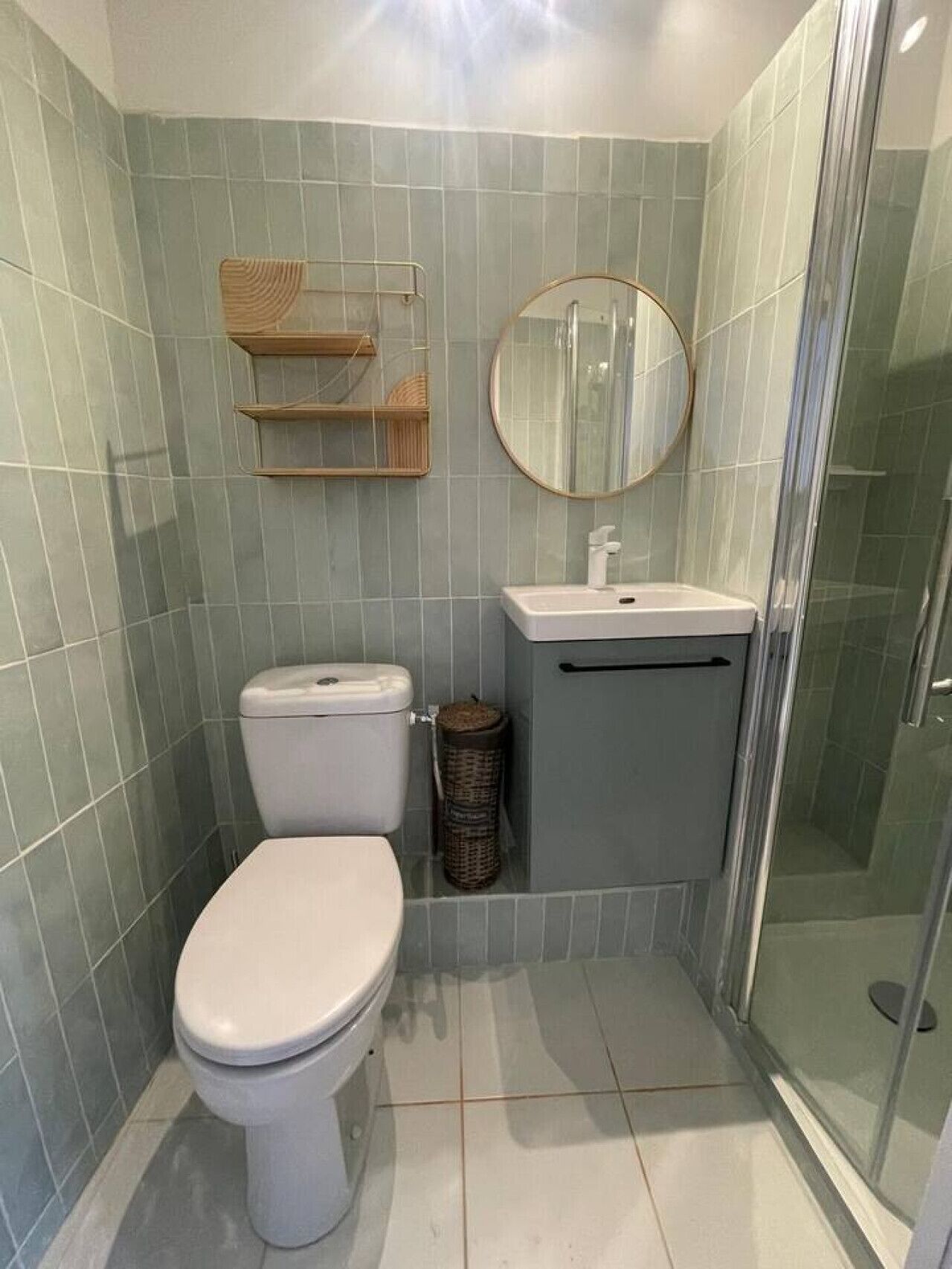 Een kleine badkamer met toilet, wastafel, spiegel en douche.