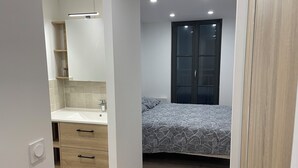 A compact bedroom with a bed, a wardrobe, and a bathroom with a sink and mirror. - Town house, 4 bedrooms / 4 bathrooms, large living room and terrace (CARCASSONNE)