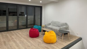 A modern living room with a grey sofa, a red and a yellow bean bag chair, a small wooden table, and a grey covered couch. - Town house, 4 bedrooms / 4 bathrooms, large living room and terrace (CARCASSONNE)