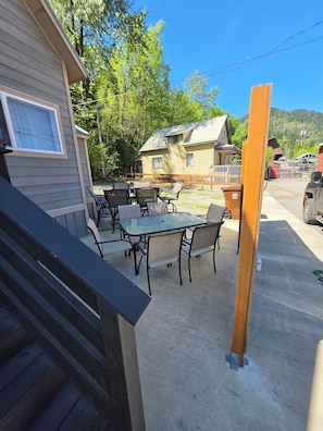 A patio area with a table and chairs, a wooden fence, and a building in the background.